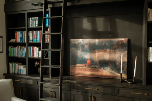 Ladder next to modern cabinet set with printed photograph and candle as design decoration