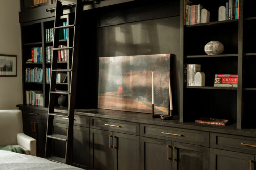 Ladder next to modern cabinet set with printed photograph and candle as design decoration