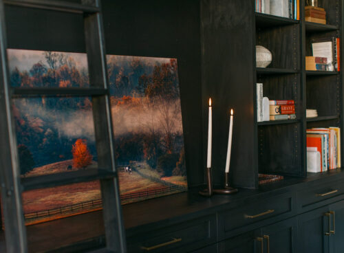 Ladder next to modern cabinet set with printed photograph and books and candle as design decoration