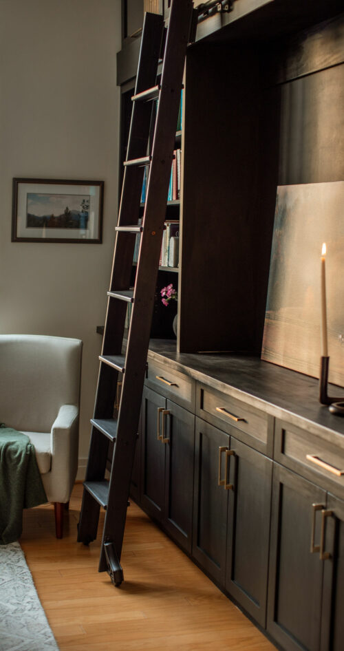 Ladder next to modern cabinet set with printed photograph and candle as design decoration