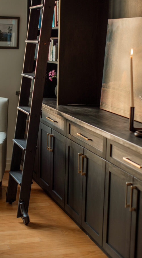 Ladder next to modern cabinet set with printed photograph and candle as design decoration