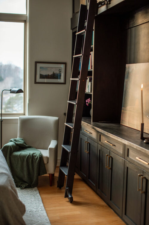 Ladder next to modern cabinet set with printed photograph and candle as design decoration